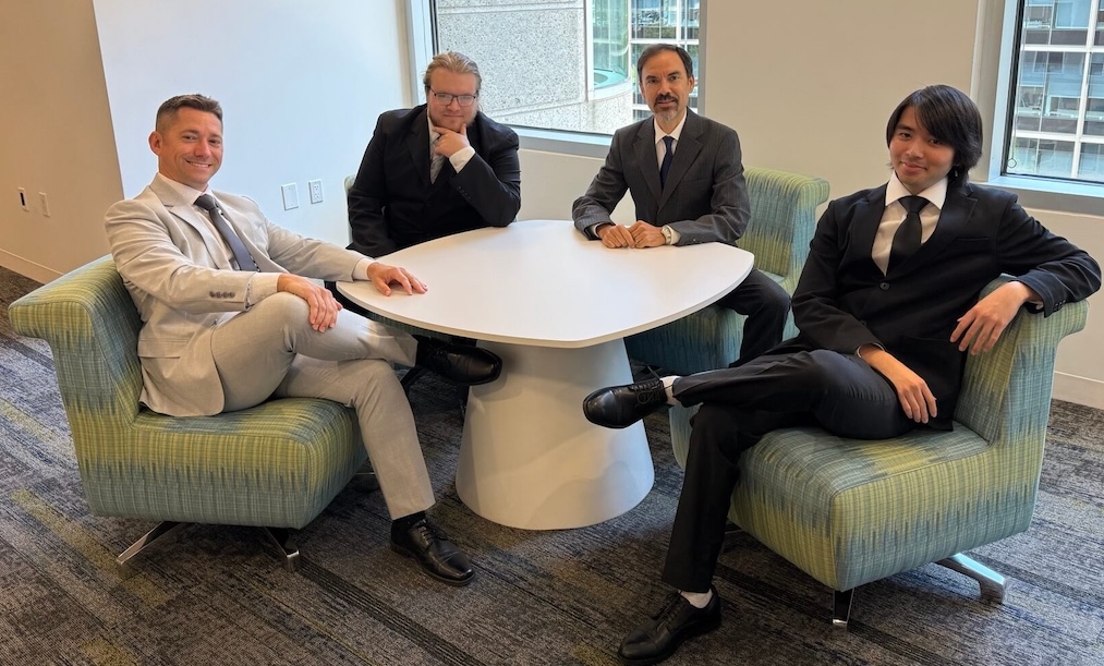 men sitting in a half circle at a round table. Liona's washington dc team